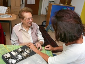 Seniorin schaut mit Betreuerin Fotos an